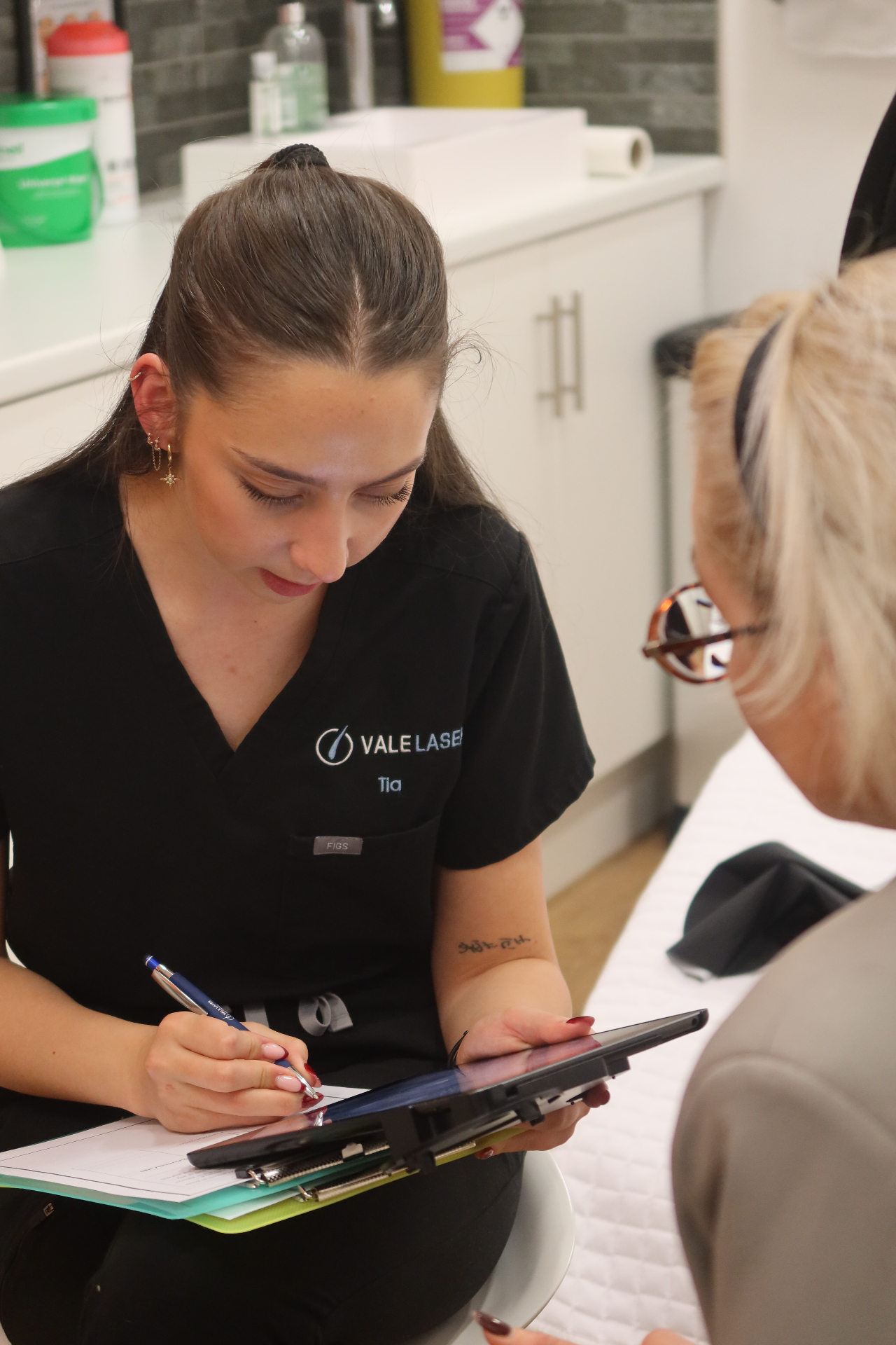Vale Laser Aesthetics clinician Tia completing a personalised consultation form with a client in our Cardiff clinic, reviewing medical history and skin assessment before treatment